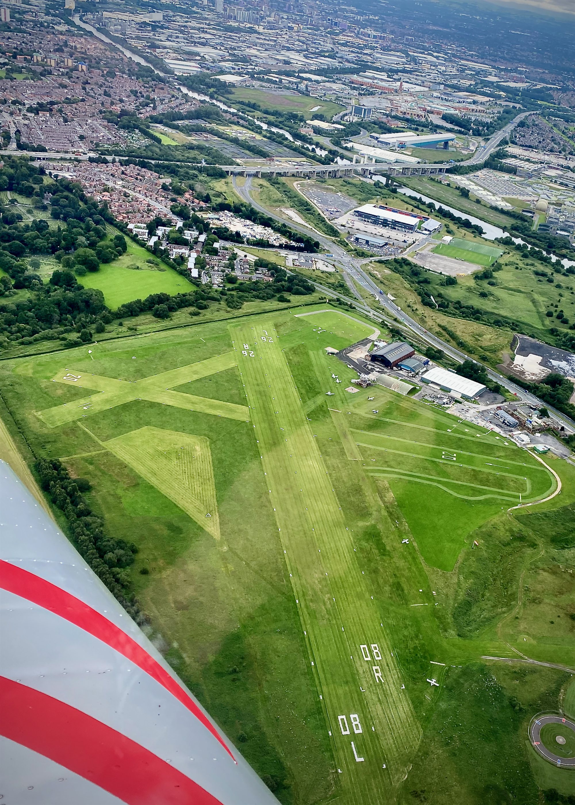 Aerial view over a UK city and airfield from the cockpit